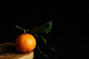 Ripe mandarin with leaves on a black background