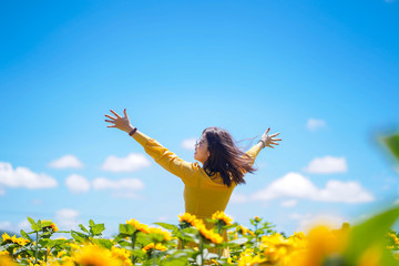 Happy carefree summer woman in sunflower field in spring. Cheerful multiracial Asian woman smiling with arms raised up.