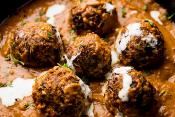 Malai Kofta is a Mughlai Speciality dish served in a bowl or pan over moody background. selective focus