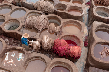 Man working in Tanneries of Fes Old tanks with color paint for leather. Morocco Africa