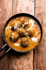 Malai Kofta is a Mughlai Speciality dish served in a bowl or pan over moody background. selective focus