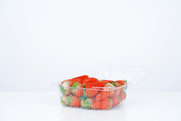 Plastic box with strawberries on white background.