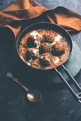 Malai Kofta is a Mughlai Speciality dish served in a bowl or pan over moody background. selective focus