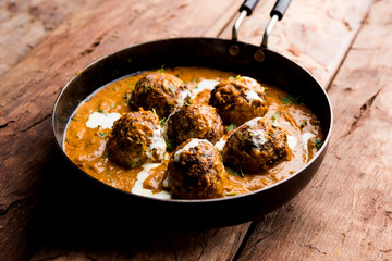 Malai Kofta is a Mughlai Speciality dish served in a bowl or pan over moody background. selective focus