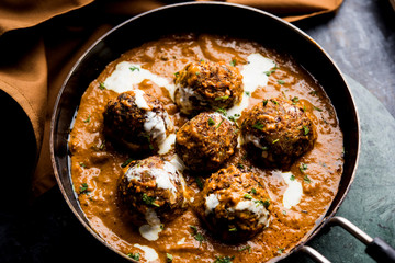 Malai Kofta is a Mughlai Speciality dish served in a bowl or pan over moody background. selective focus