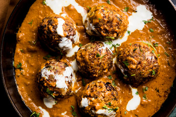 Malai Kofta is a Mughlai Speciality dish served in a bowl or pan over moody background. selective focus