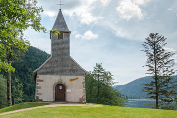 Fototapeta na wymiar Longemer France, 15 july 2018. Little chapel Longemer lake at the Vosges mountains in France.