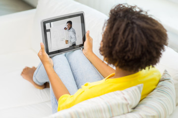 e-learning, education and technology concept - african american woman watching webinar on tablet computer at home
