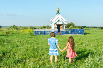Девочки идут в деревенскую часовню взявшись за руки.