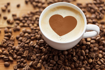 valentines day and hot drinks concept - close up coffee cup with heart stencil picture and roasted...