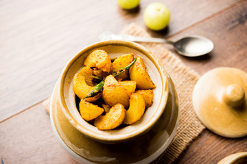 Homemade Gooseberry or amla Pickle/ or Aavle ka Achar in a bowl or barni over moody background. ...