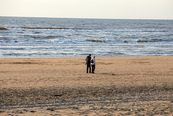 A woman and a man are walking on a sunny day along the beach in Katwijk. Netherlands