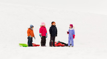 Fototapeta na wymiar childhood, sledging and season concept - group of happy little kids with sleds in winter