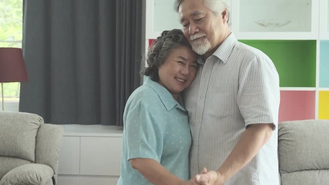 Senior couple dancing together in living room. Retired old Asian male and female, dancing together in their home, happy smile. Senior lifestyle concept.