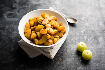 Homemade Gooseberry or amla Pickle/ or Aavle ka Achar in a bowl or barni over moody background.  selective focus