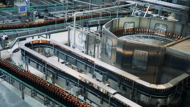 Brewery plant with transporting equipment and glassy bottles moving along it
