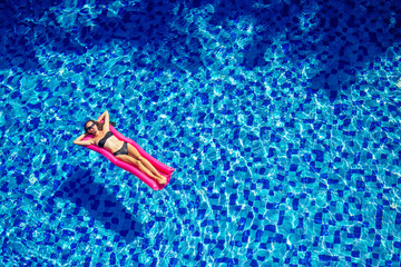 beautiful brunette girl floating on mattresses in the pool.fitness female model in black bikini...