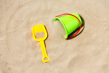 toys, childhood and summer concept - bucket and shovel on beach sand