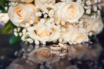 wedding rings and bouquet on black glass