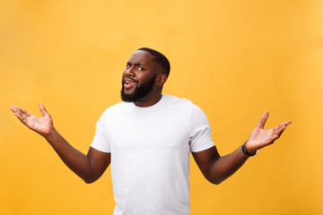 Portrait of african american man with hands raised in shock and disbelief. Isolated over yellow background.