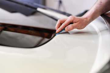 Man squeegeeing water from the window and window tinting film. Professional car window tinting services