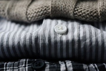 Fototapeta na wymiar a stack of things for the cold weather: cotton shirts-striped and checkered, and beige wool sweater