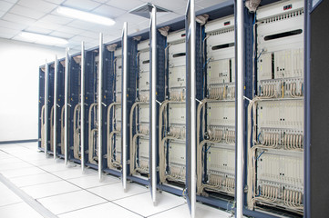 Network server room with Close rack is row in white floor and white ceiling , high performance computers running processes , Rack is open door show telecommunication technology
