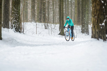 Cyclist on cyclocross bike trails in the snowy forest in winter. Downhill riding a snowy slope. Winter workout outdoors concept
