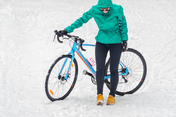 Cyclist woman stands near his bike. Bike trails in the snowy forest in winter. Winter workout outdoors concept