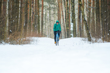Cyclist on cyclocross bike trails in the snowy forest in winter. Winter workout outdoors concept