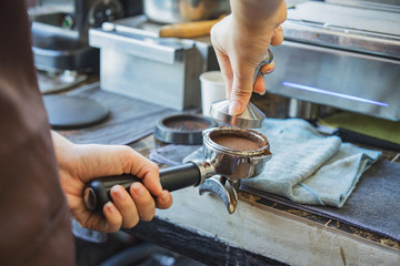 Barista using tamper to makes coffees in coffee bar