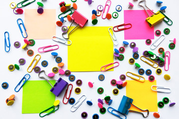 Colorful stationary, back to school, office, business and education concept. School and office supplies paper clips, pins, notes, stickers on white background, flatlay. Mock up. Top view, close up