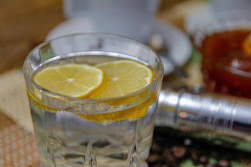 Coffee on wooden table and old manual coffee grinder. Mineral water and traditional plum jam with lemon. coffee beans spilled on the table.