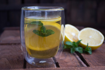 tea with lemon and mint in a glass on a wooden background