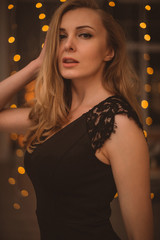 Portrait of Beautiful Woman in Lights. Fashion Dress and MakeUp. Christmas Santa. Elegant Lady in Red Dress over Christmas Tree Lights Background. Happy New Year.