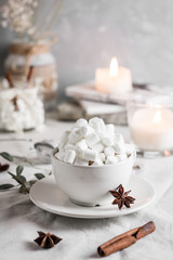 Fototapeta na wymiar Cocoa with marshmallow and straws in the cup on the table with candles for the winter holidays