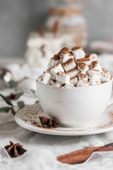 Cocoa with marshmallow and straws in the cup on the table with candles for the winter holidays