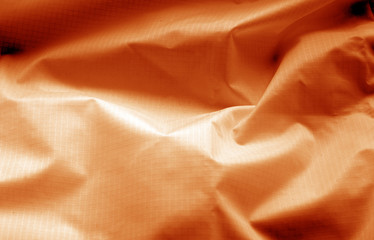 Crumpled transparent plastic surface in orange color.
