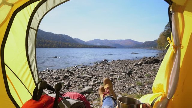 Altai. Camping woman lying in tent Close up of Girl feet wearing hiking boots relaxing on vacation POV. Two videos in one.