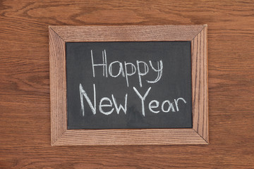top view of 'happy new year' text on chalk board with wooden background