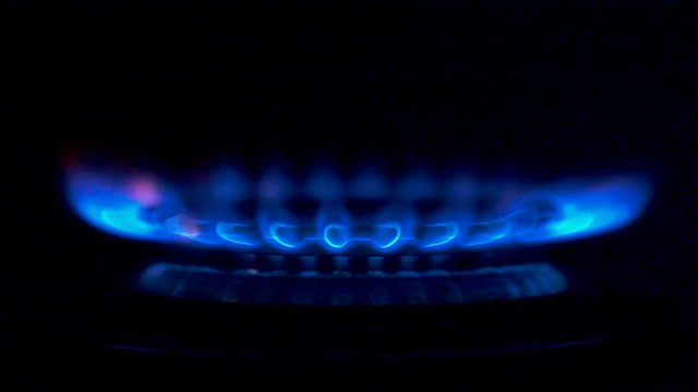Fire igniting on a gas stove. From a state of complete darkness, blue flame of gas slowly igniting, bringing warmth and heat. Slow motion close-up shot