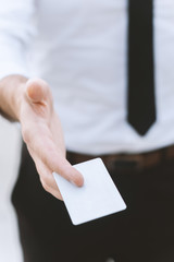 Male hand with white empty business card , close-up photo with selective focus