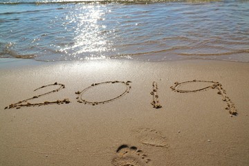 Happy New year 2019 with the waves beat at the beach, reflection of sunlight  and foot print. Nature and festival concept.