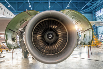 Aircraft engine jet with open hood on the sides in the hangar for maintenance