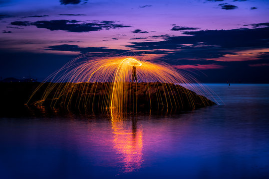 The beautiful fire dancer swing fire dancing show on the beach with dark clouds,dark sky background