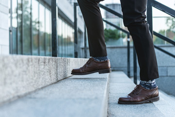  Сlose-up of male legs in business trousers and shoes walking up the stairs