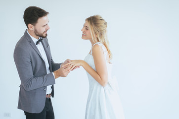Groom hand putting or wearing a wedding ring to bride finger in wedding day on white background