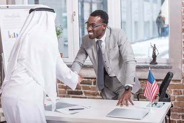 African american businessman shaking hands with arabic partner in office