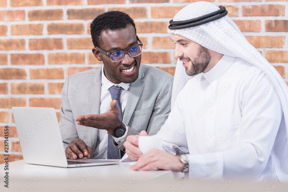 Wall mural african american businessman showing laptop in modern office