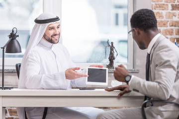Arabian businessman showing digital tablet and smiling in office